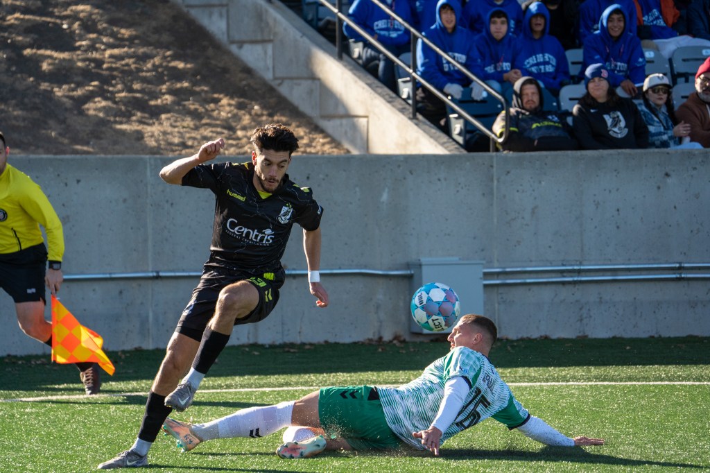 Younes Boudadi dribbling past a sliding Greenville Triumph player