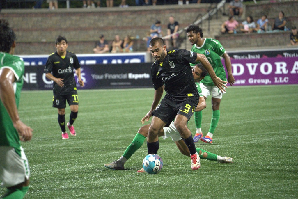Pato Botello Faz shielding the ball against a New York Cosmos defender.